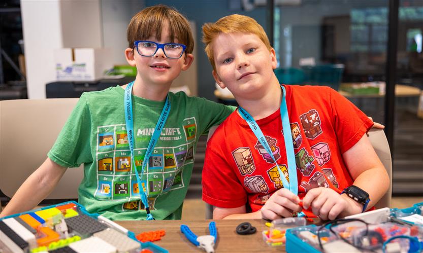 A boy wearing a red shirt and a boy wearing a green shirt smile
